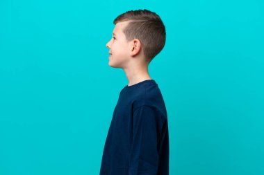 Küçük çocuk mavi arka planda izole edilmiş görünüyor.