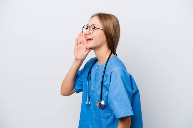 Young nurse doctor woman isolated on white background shouting with mouth wide open to the lateral