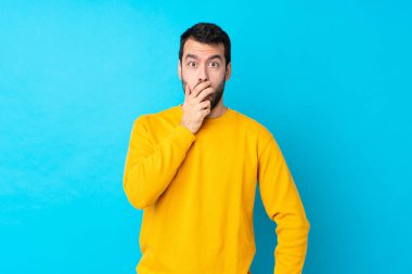 İzole edilmiş mavi arka plan üzerinde genç beyaz adam sağa bakarken şaşırdı ve şok oldu.