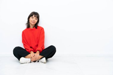 Beyaz arka planda soyutlanmış, kalçasında kollarıyla poz veren ve gülümseyen genç, melez bir kadın.