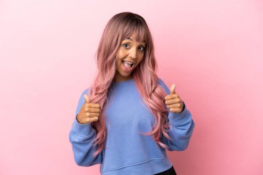 Pembe saçlı melez bir kadın pembe arka planda izole edilmiş bir şekilde jest yapıyor.