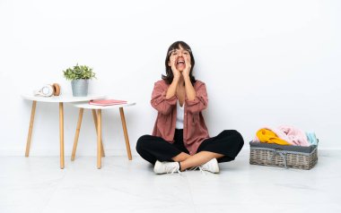 Genç ırk katlayan kadın, beyaz arka planda soyutlanmış bir şekilde yerde oturuyor bağırıyor ve bir şey duyuruyor.