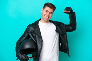 Mavi arka planda izole edilmiş motosiklet kasklı beyaz bir adam güçlü bir jest yapıyor.