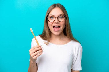 Genç Litvanyalı kadın, yalıtılmış arka planda dişlerini fırçalıyor, şaşırmış ve şok olmuş bir yüz ifadesi var.