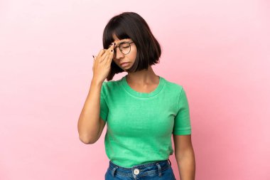 Pembe arka planda soyutlanmış, başı ağrıyan genç melez bir kadın.