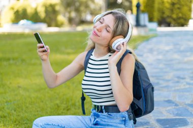 Açık havada cep telefonu kullanan genç sarışın kadın.