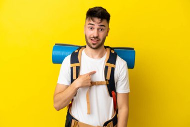 Sarı arka planda yalıtılmış büyük sırt çantalı, beyaz, genç bir adam.