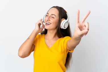 Genç İspanyol kadın soyutlanmış beyaz arka planda müzik dinliyor ve şarkı söylüyor.
