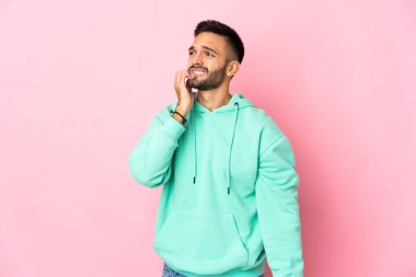 Pembe arka planda izole edilmiş genç beyaz adam biraz gergin.