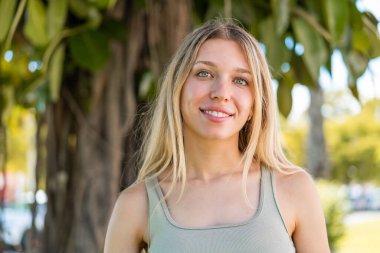 Açık havada genç sarışın bir kadın Neşeli bir ifadeyle