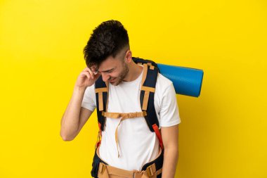 Sarı arka planda izole edilmiş büyük sırt çantalı beyaz bir adam gülüyor.