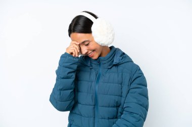 Kış kulaklığı takan genç İspanyol kadın beyaz arka planda izole edilmiş gülüyor.