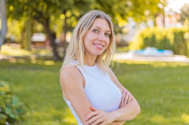 Sarışın genç bir kadın kolları bağlı ve ileriye bakıyor.