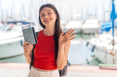 Genç, güzel Ukraynalı bir kadın elinde pasaport, elinde mutlu bir ifadeyle selamlıyor.