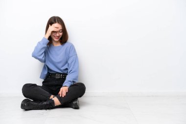 Genç Ukraynalı bir kadın beyaz arka planda yalnız başına oturmuş gülüyor.