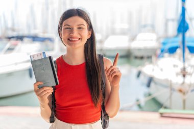 Genç, güzel Ukraynalı bir kadın elinde pasaport tutarak harika bir fikri işaret ediyor.