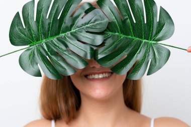 Beyaz arka planda izole edilmiş beyaz bir kadın elinde mutlu bir ifadeyle bir palmiye yaprağı tutuyor. Portreyi kapat