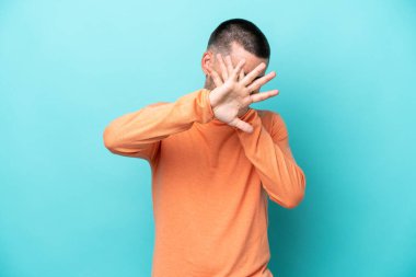 Kafkasyalı genç adam mavi arka planda izole edilmiş gergin eller öne doğru uzanıyor.