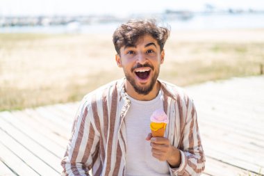 Açık havada kornet dondurması olan yakışıklı bir Arap. Şaşırmış ve şok olmuş bir yüz ifadesi var.