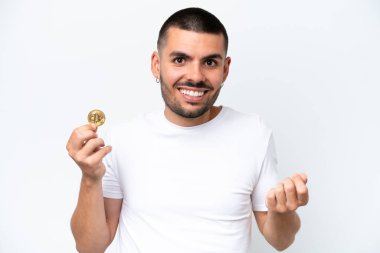 Beyaz arka planda izole edilmiş bitcoin tutan genç beyaz bir adam para hareketi yapıyor.