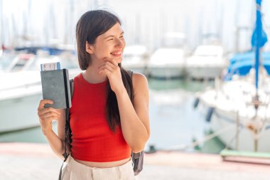 Genç, güzel Ukraynalı bir kadın elinde pasaportuyla dışarıda bir fikir üretiyor ve bakıyor.