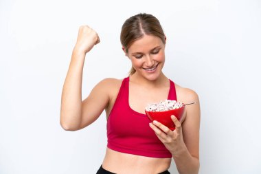 Genç, güzel sarışın kadın kahvaltı sütü içiyor. Beyaz arka planda, zaferi kutluyor.