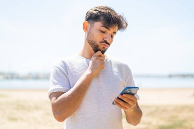 Dışarıdaki yakışıklı Arap adam düşünüp bir mesaj yolluyor.