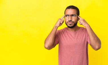 Sarı arka planda izole edilmiş genç latin adamın şüpheleri ve düşünceleri var.