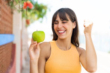 Dışarıda elmalı genç bir kadın zaferi kutluyor.