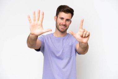 Beyaz arka planda izole edilmiş genç beyaz adam yediyi parmaklarıyla sayıyor