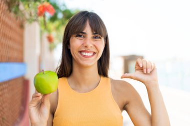 Açık havada elmalı genç bir kadın gururlu ve kendini beğenmiş.