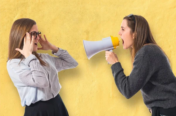 Girl shouting at her sister by megaphone — Stock Photo, Image