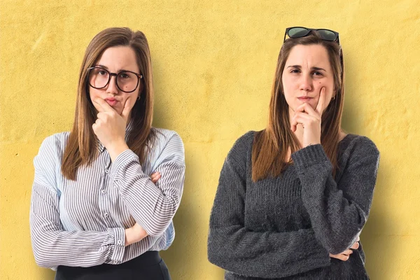 Irmãs gêmeas pensando sobre fundo branco — Fotografia de Stock