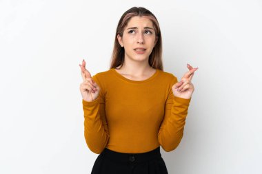 Beyaz arka planda izole edilmiş beyaz tenli genç bir kadın parmaklarını çapraz yapıp en iyisini diliyor.