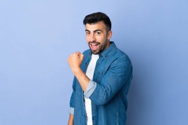 İzole edilmiş mavi arka planda beyaz bir adam zaferi kutluyor.