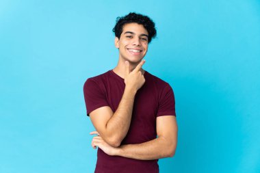 Genç Venezuelalı adam mavi arka planda izole edilmiş mutlu ve gülümsüyor