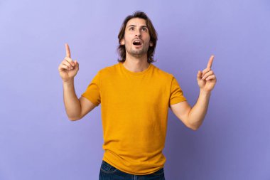 Mor arka planda soyutlanmış yakışıklı bir adam şaşırmış ve yukarı bakıyor.