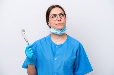 Beyaz arka planda izole edilmiş aletler tutan beyaz dişçi kadın.