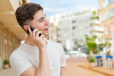 Genç ve yakışıklı bir adam cep telefonuyla sohbet ediyor.