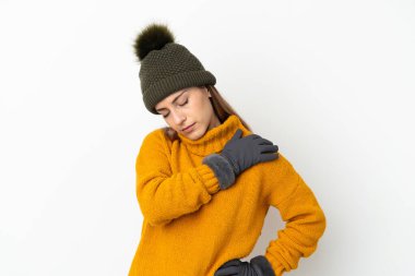 Kış şapkalı genç kız, beyaz arka planda izole edilmiş, omuz ağrısından muzdarip, çabaladığı için.