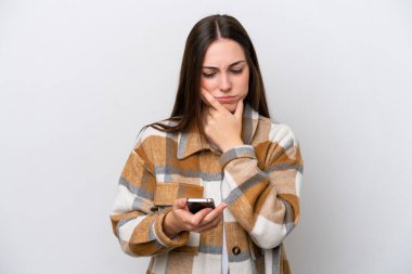 Beyaz arka planda izole edilmiş genç bir kız düşünüyor ve bir mesaj gönderiyor.