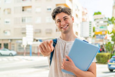 Dışardaki genç ve yakışıklı öğrenci kendine güvenen bir ifadeyle seni işaret ediyor.