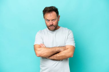 Mutsuz bir ifadeyle mavi arka planda izole edilmiş orta yaşlı beyaz bir adam.