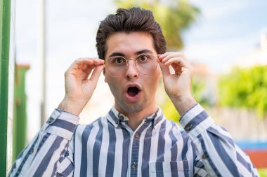 Gözlüklü ve şaşkın bakışlı genç yakışıklı adam.