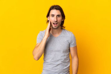 Sarı arka planda mahsur kalmış yakışıklı ve şaşırmış yüz ifadesi olan genç bir adam.