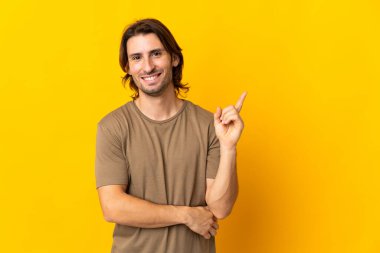 Sarı arka planda soyutlanmış yakışıklı genç adam mutlu ve dik duruyor.