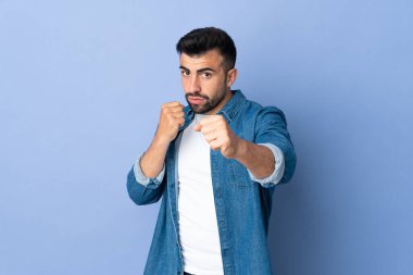 İzole edilmiş mavi arka planda dövüşen beyaz adam.