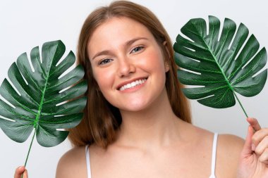 Beyaz arka planda izole edilmiş beyaz bir kadın elinde mutlu bir ifadeyle bir palmiye yaprağı tutuyor. Portreyi kapat