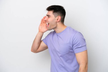 Beyaz arka planda izole edilmiş genç beyaz adam ağzı sonuna kadar açık bağırıyor.