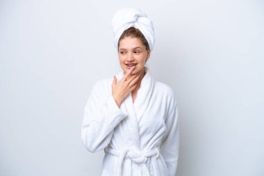 Teenager Russian girl in a bathrobe isolated on white background looking up while smiling